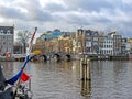 Dutch flag on the boat with bridge and Amsterdam famous duch traditional Flemish brick buildings Royalty Free Stock Photo